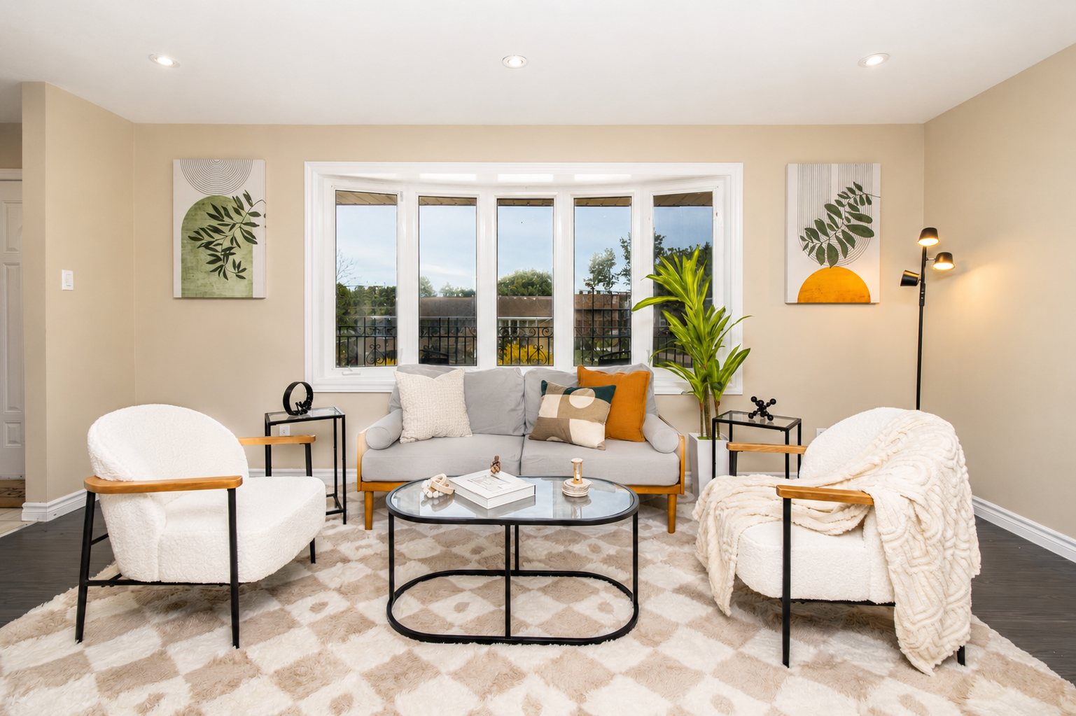 Sunlit living room with a bay window, light furniture and modern art